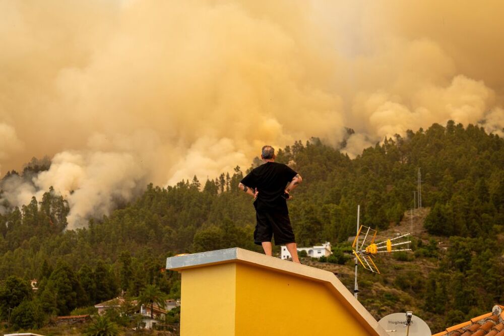 Un vecino observa desde el tejado de una casa el incendio forestal declarado en  la Palma, cerca de una vivienda, a 15 de julio de 2023, en Puntagorda, La Palma, Canarias (España). Este incendio declarado en la madrugada de hoy en zona urbano forestal en   / EUROPA PRESS