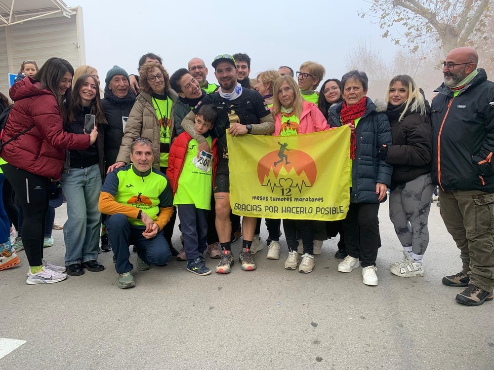 Daniel Caballero posa junto a su familia con la bandera del reto contra el cáncer. 