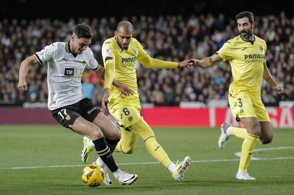 El delantero del Valencia Yaremchuk (i) protege el balón ante Capoue